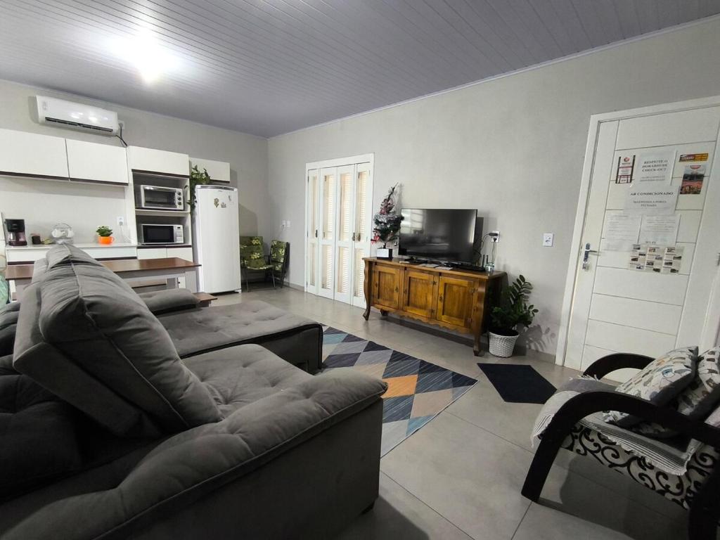ein Wohnzimmer mit Sofa und Fernseher in der Unterkunft Casa Finger 800m do Centro e do Núcleo de casas Enxaimel anfitriões residem ao lado in Ivoti