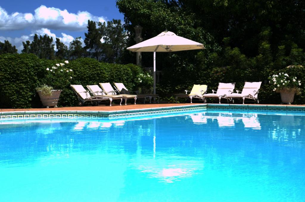 a swimming pool with chairs and an umbrella at Clos Malverne Wine Estate in Stellenbosch