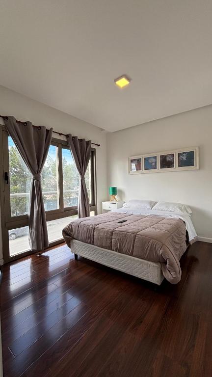 ein Schlafzimmer mit einem Bett und einem großen Fenster in der Unterkunft Costanera Sur Departamento in Río Gallegos