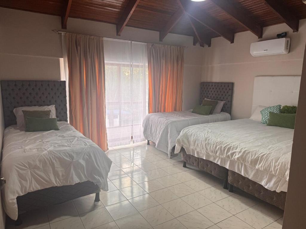 ein Schlafzimmer mit zwei Betten und einem Fenster in der Unterkunft Tivives Kikala Lodge 2 in Puntarenas