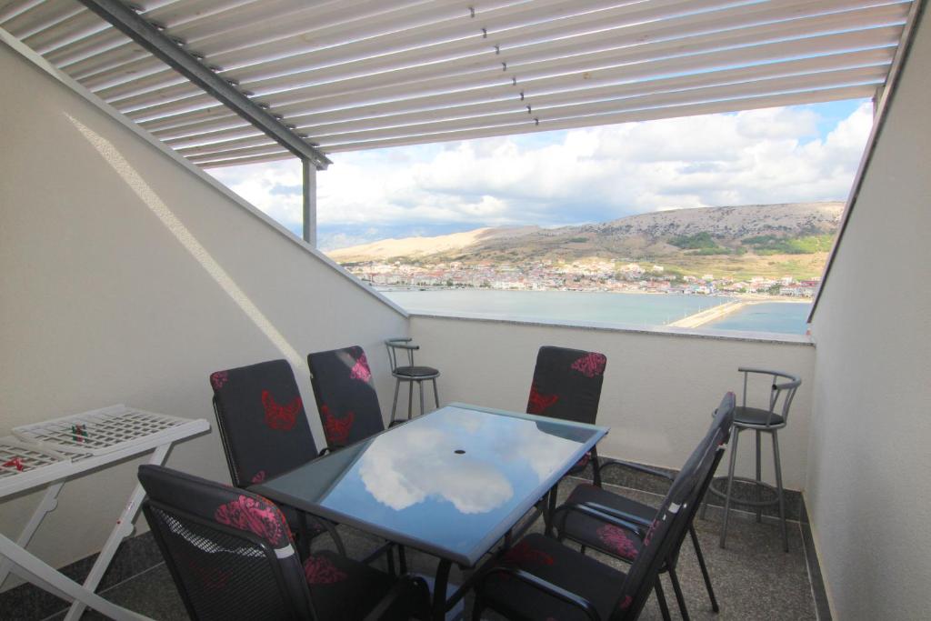 balcón con mesa, sillas y vistas al agua en Apartments Sv. Jelena 2, en Pag