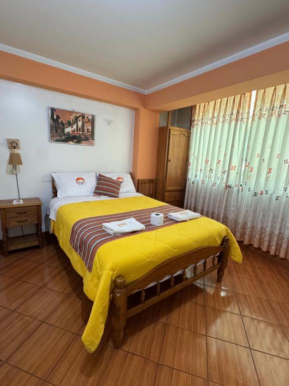 ein Schlafzimmer mit einem großen Bett mit einer gelben Decke in der Unterkunft Lhotse Hostel B&B in Huaraz