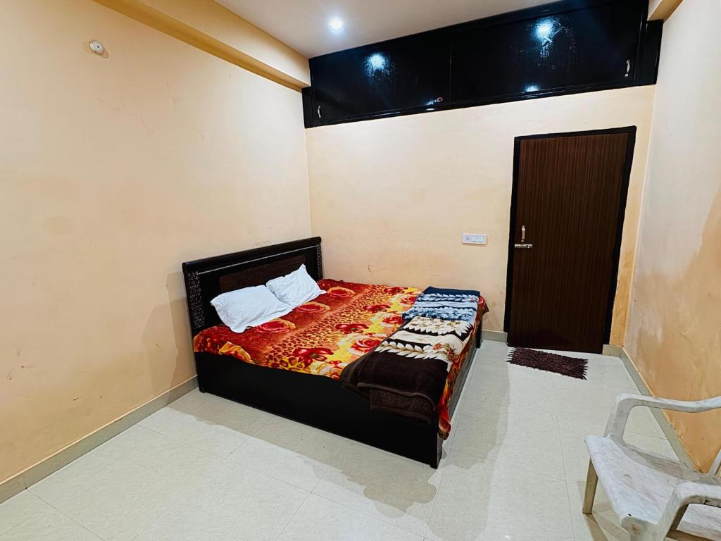 ein Schlafzimmer mit einem Bett, einem Stuhl und einer Tür in der Unterkunft shri radha ji guest House in Vrindāvan