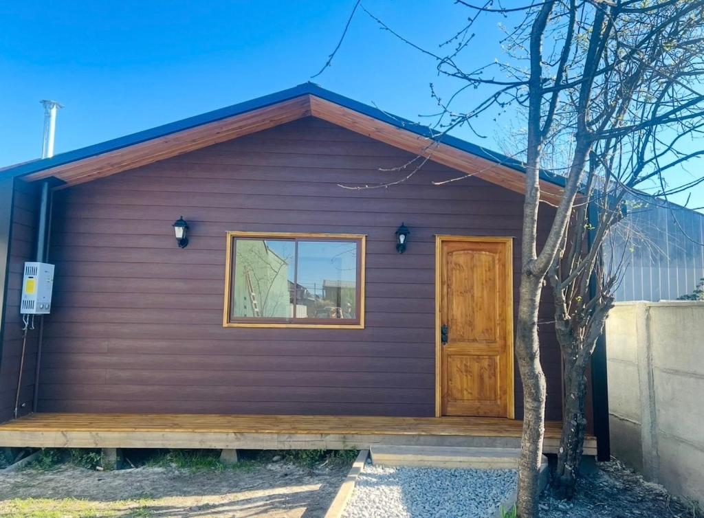 een paars huis met een deur en een boom bij Cómoda y acogedora cabaña a pasos del centro de Villarrica in Villarrica