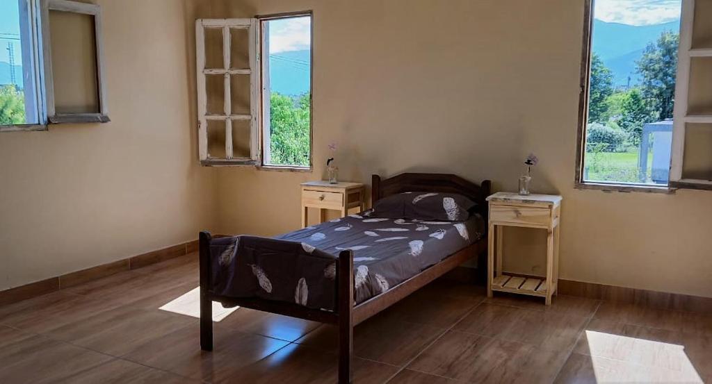 een slaapkamer met een bed en 2 tafels en ramen bij La Calandria in Cerrillos