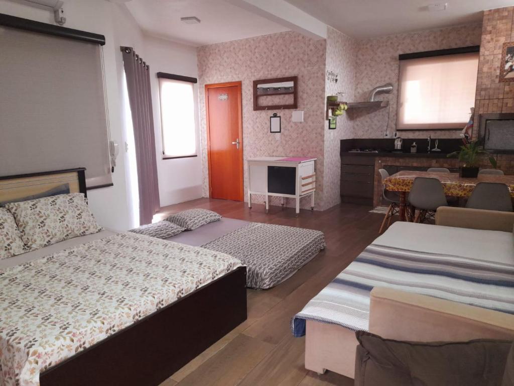 una camera d'albergo con due letti e una cucina di ESTÚDIO "Coisa de Daiane" a São Gabriel