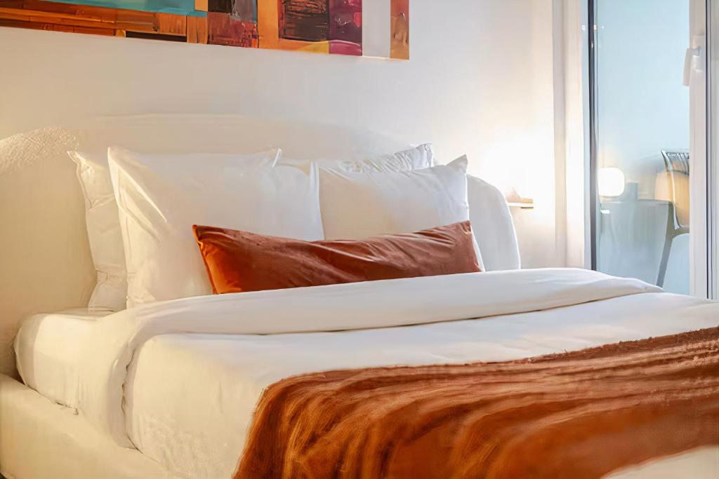 un letto bianco con lenzuola e cuscini bianchi di Charming condo in Rosemont a Montréal