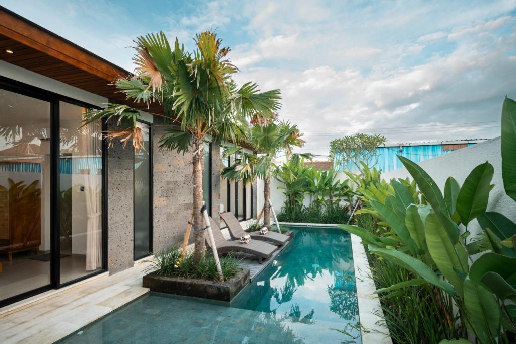 een buitenzwembad met palmbomen en een huis bij Snuggy Shack Villas in Munggu