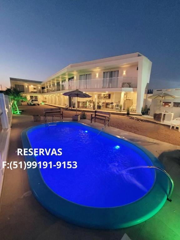 a large blue swimming pool in front of a building at Pousada Garden in Tramandaí