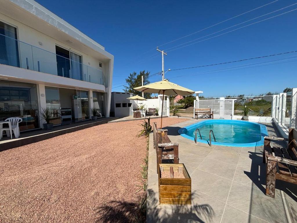 een zwembad met een parasol naast een gebouw bij Pousada Garden in Tramandaí