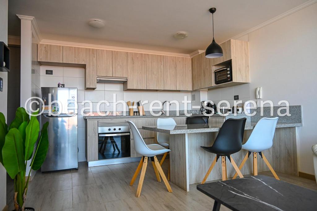 a kitchen with wooden cabinets and a table and chairs at Beach Rent La Serena in La Serena