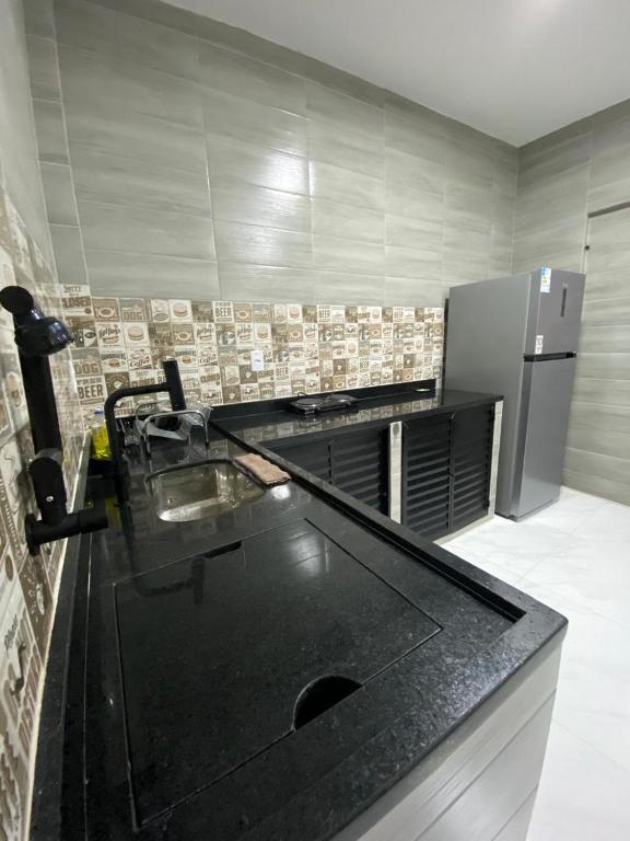 a kitchen with a black counter top and a refrigerator at Sua Estadia Angra - Casa de 2 Quartos no Centro de Angra in Angra dos Reis