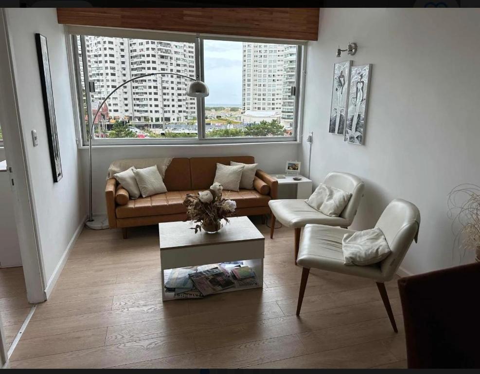 een woonkamer met een bank en twee stoelen bij Enfrente al mar Servicio de playa Limpieza diaria Estacionamiento Sábanas y toallas Gimnasio Recepción 24 hs A pasos del puerto y Gorlero in Punta del Este