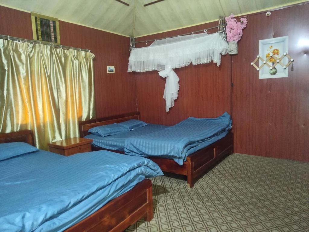 two twin beds in a room with wood walls at ha giang loop & tour in Bản Kin