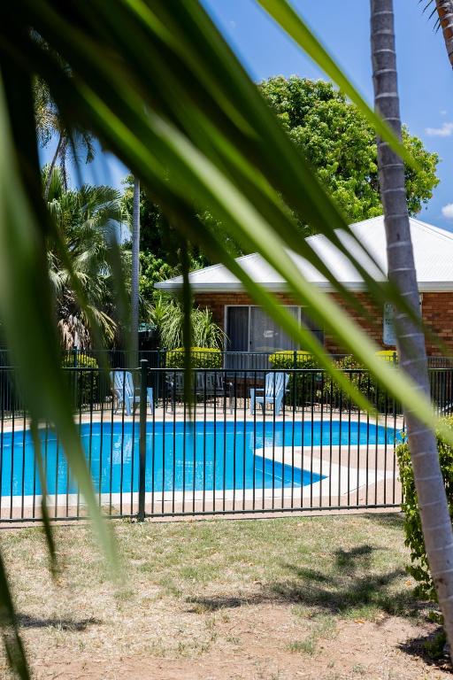 a pool with a fence and palm trees at Maraboon Motor Inn in Emerald