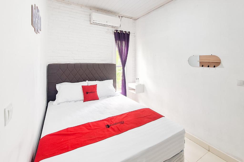 a bedroom with a white bed with a red pillow at RedDoorz at Hotel Lavender Kertajati in Gadel