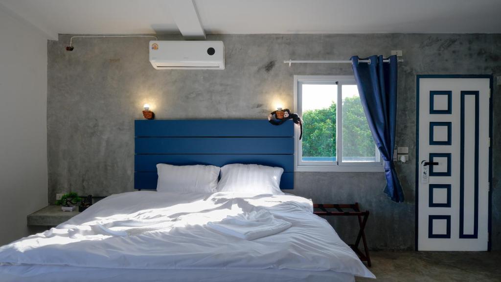 a bed with a blue headboard in a bedroom at Three Monkeys Mae Nam beach in Mae Nam