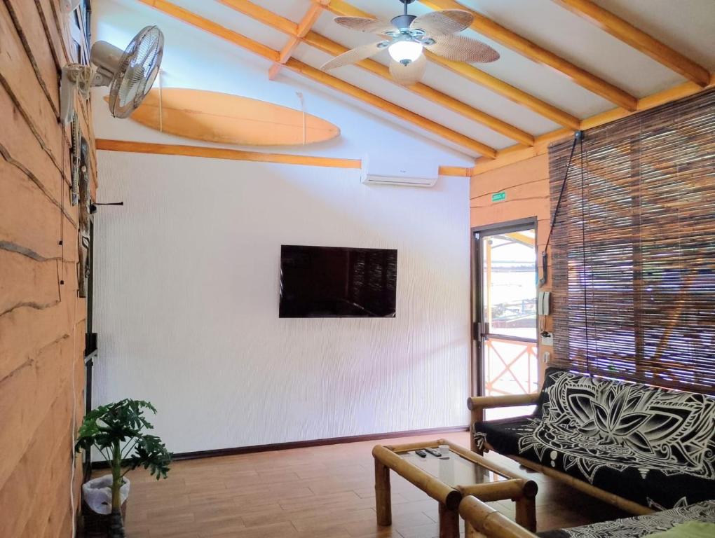 a living room with a couch and a tv on a wall at Domi Hostel in Dominical