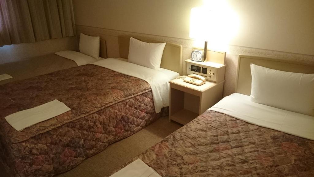 a hotel room with two beds and a lamp at Hotel Crown Hills Kanazawa in Kanazawa