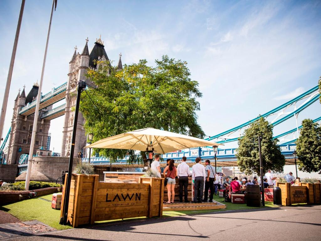 people standing under an umbrella in front of a bridge at The Tower Hotel, by Thistle in London