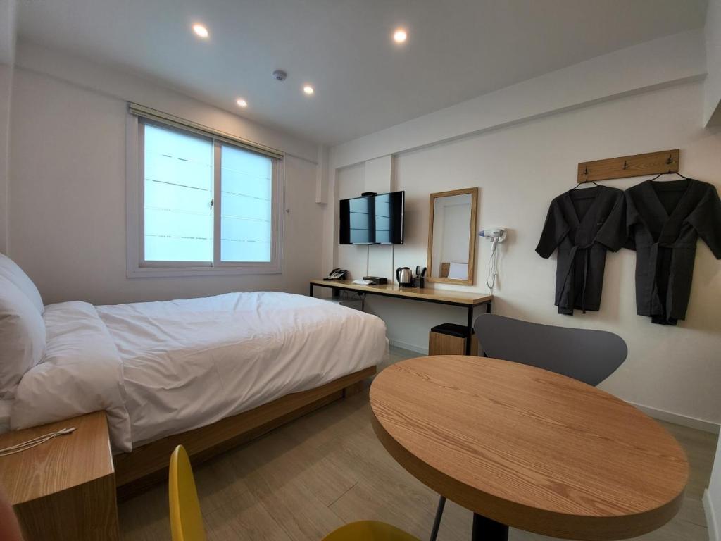 een slaapkamer met een bed, een bureau en een tafel bij Haemil Stay in Daegu