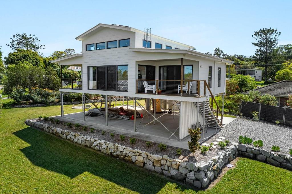 een groot wit huis met een stenen muur bij The Grevilleas in Woombah