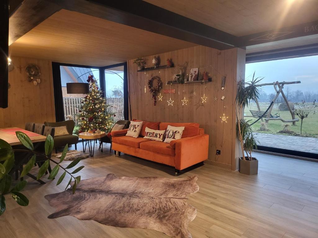 ein Wohnzimmer mit einem orangenen Sofa und einem Weihnachtsbaum in der Unterkunft Białczańskie Bacówki 2, 4sypialnie in Białka Tatrzańska