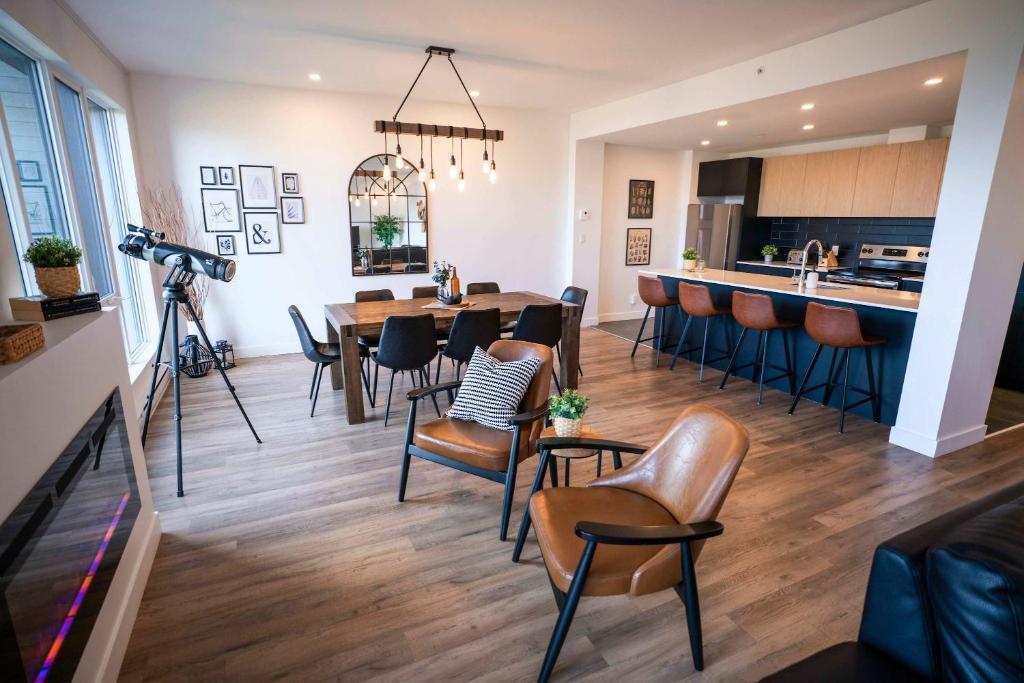 un salon avec une table et des chaises et une cuisine dans l'établissement 204 - Luxury Obsidian Condo - Elegance & Pool, à Baie-Saint-Paul