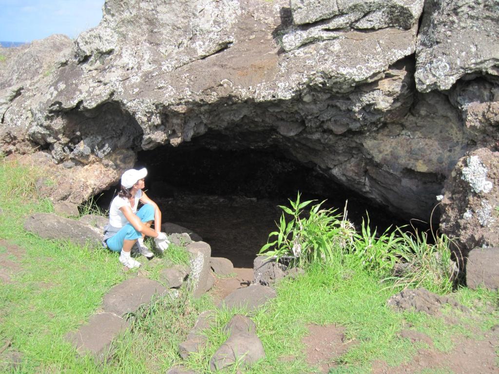 two people sitting in front of a cave at Cabañas Moai in Hanga Roa