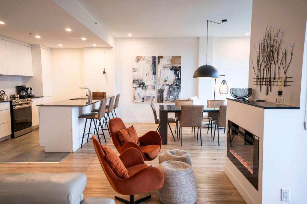 een keuken en woonkamer met een tafel en stoelen bij 205 - Modern Suite - Pool and River View in Baie-Saint-Paul
