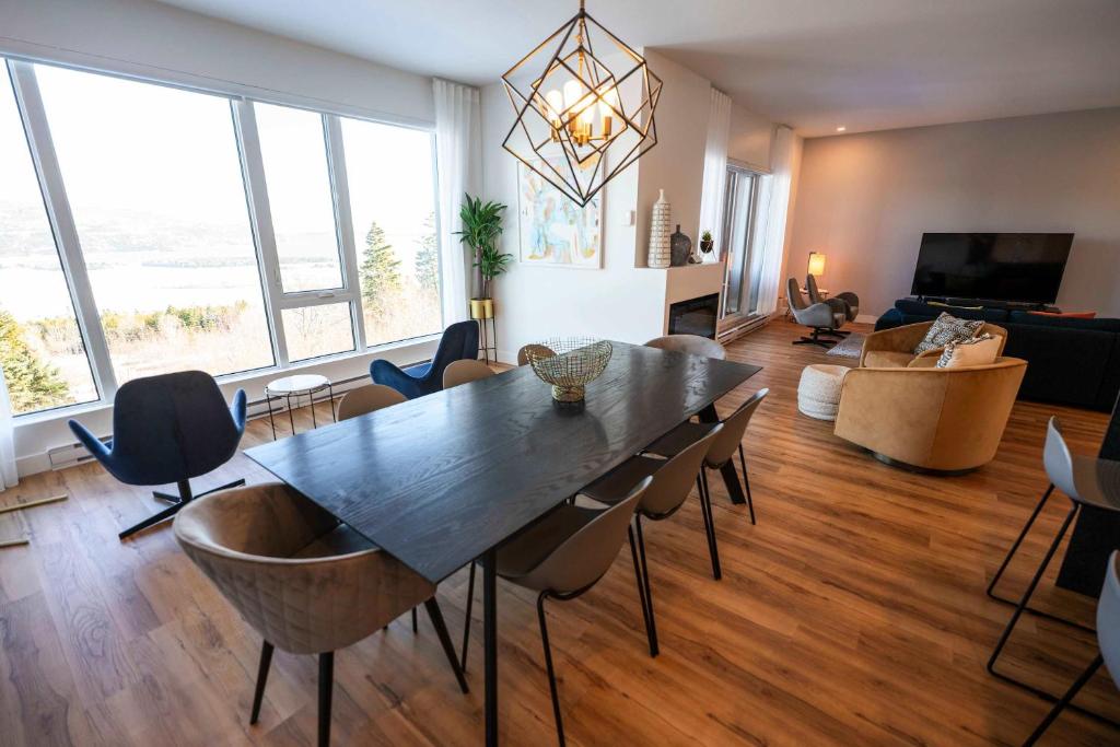 een grote woonkamer met een tafel en stoelen bij 209 - Luxury Condo - Pool & River View in Baie-Saint-Paul
