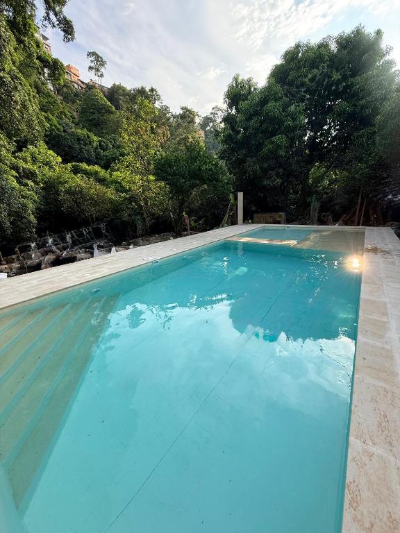 a large blue swimming pool with trees in the background at Villa Esther - Finca campestre en Mesitas del Colegio in El Colegio