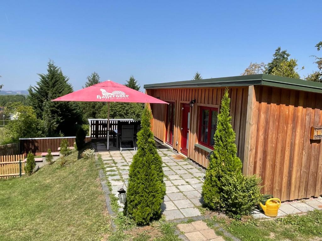 een patio met een rode paraplu voor een gebouw bij Lebensfreude in Niederdorla