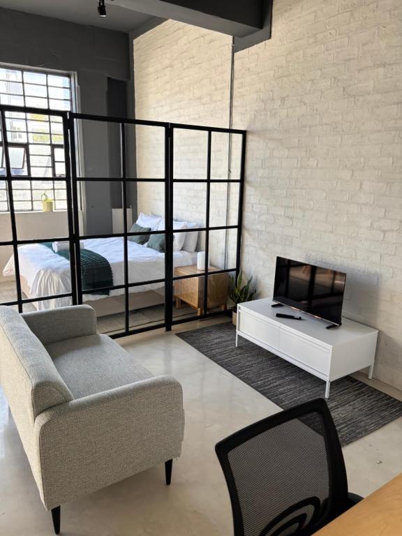a living room with a couch and a tv and a bed at Studio in Woodstock in Cape Town