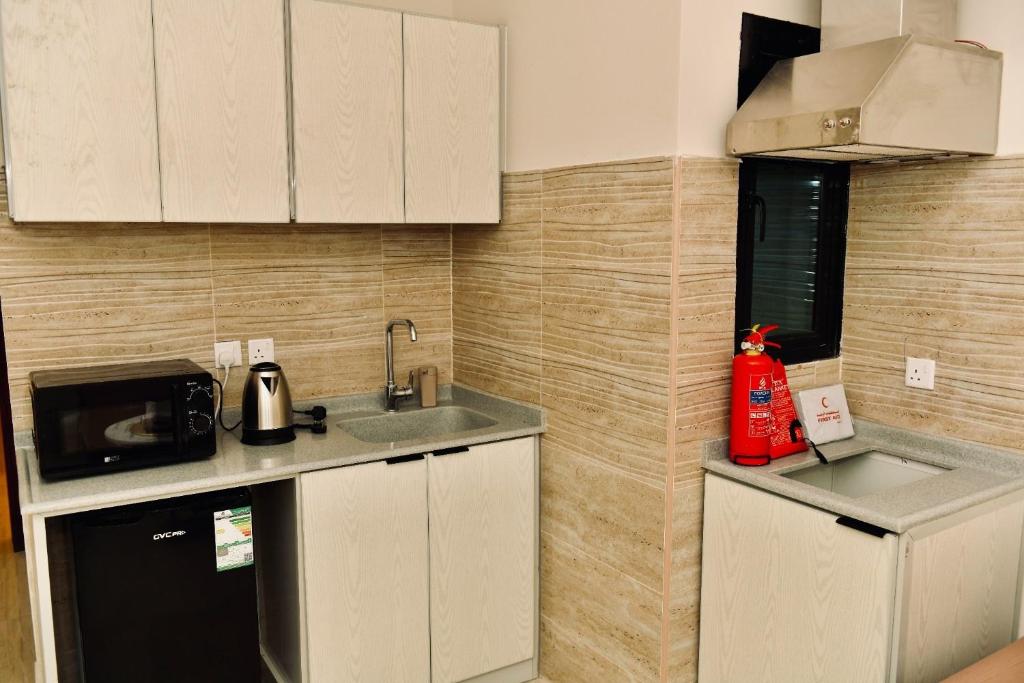 a small kitchen with a sink and a microwave at Four Stays Khobar in Al Khobar