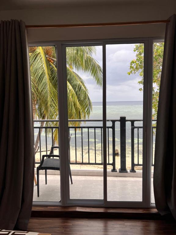 a room with a window looking out at the ocean at Alma Maldiva, Beach Hotel in Ariyaddu