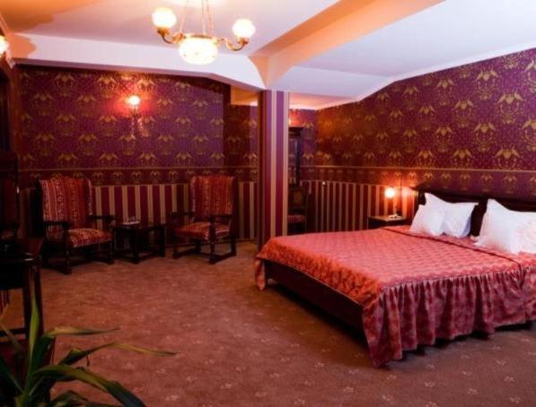 ein Hotelzimmer mit einem Bett und Stühlen darin in der Unterkunft Hotel Majestic City Center in Iaşi