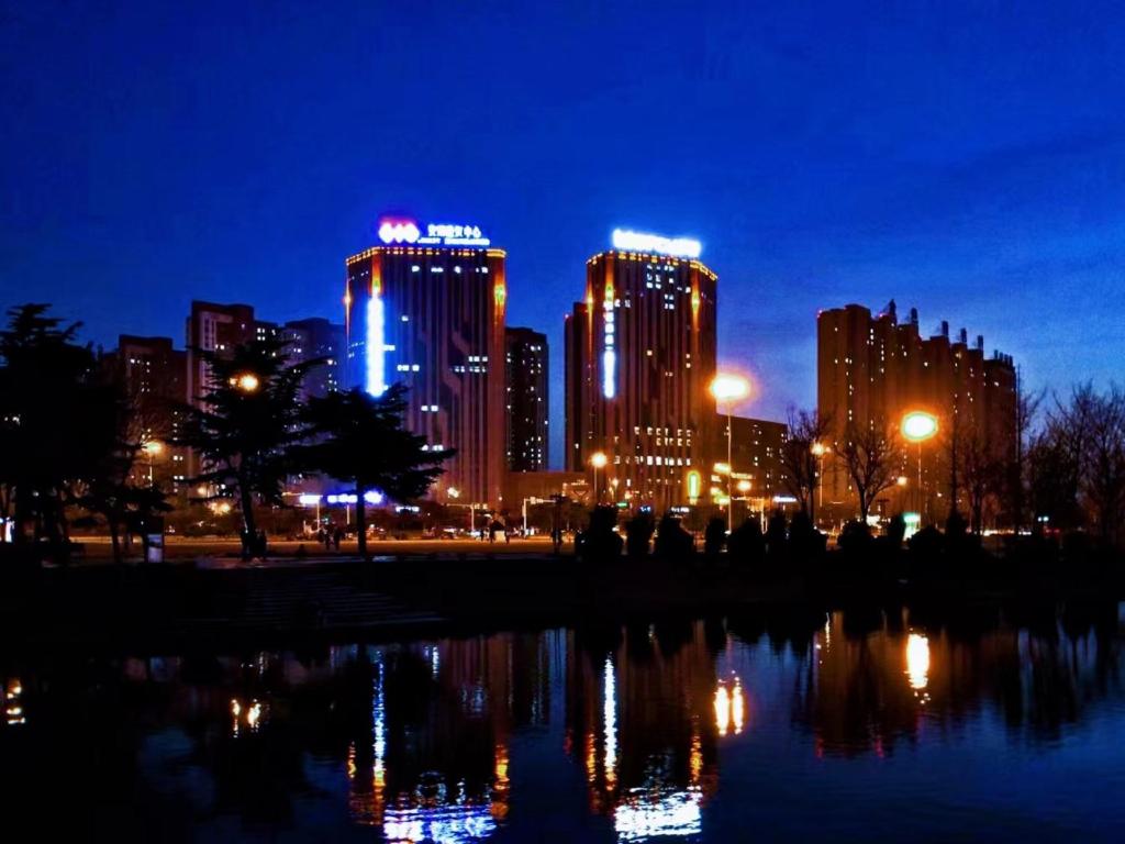 een skyline van de stad 's nachts met een reflectie in het water bij Mercure Anyang Downtown in Anyang