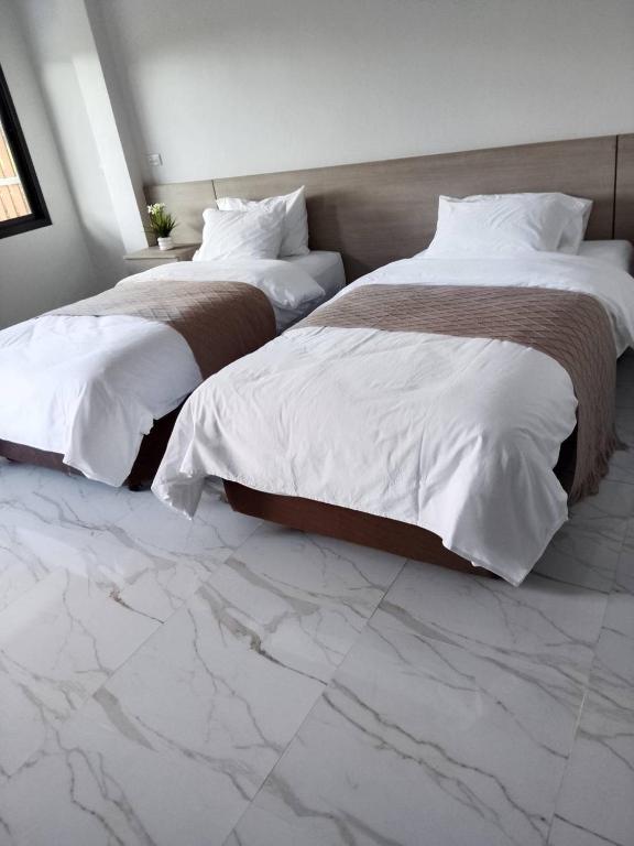 two beds in a hotel room with marble floors at Tanya's Cafe & Resort in Ban Kasang