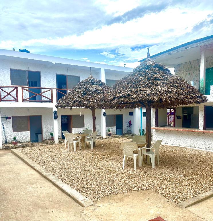 a building with tables and chairs and straw umbrellas at Spice Garden Lodge B&B in Zanzibar City