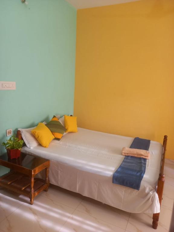 a bed with yellow and blue pillows in a room at Stay by Asharaf AS Villa in Varkala