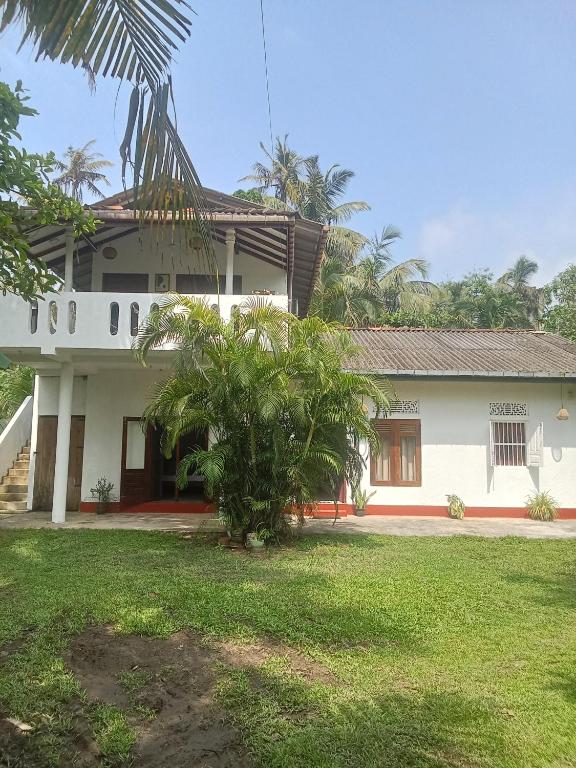a white house with a palm tree in front of it at White Horizon 2 in Ahangama
