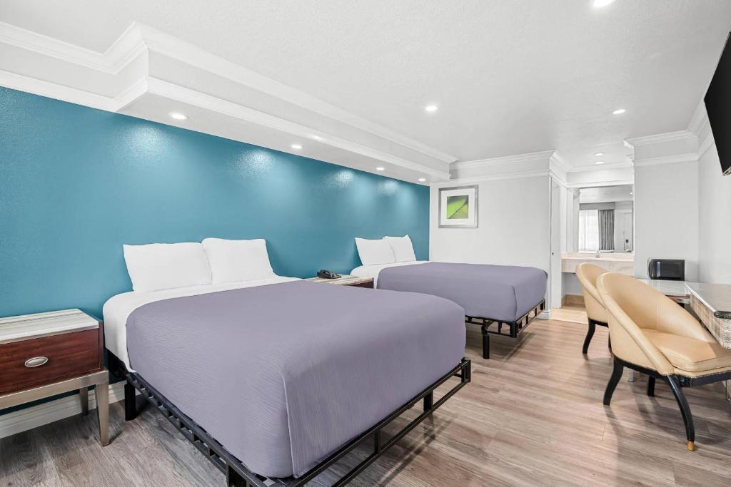 2 letti in una camera con parete blu di Rodeway Inn Commerce - Los Angeles a Commerce