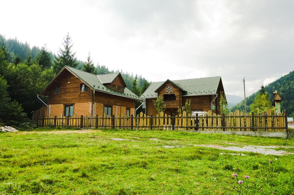 uma casa de madeira com uma cerca num campo em Kryvorizka Palanka em Mykulychyn
