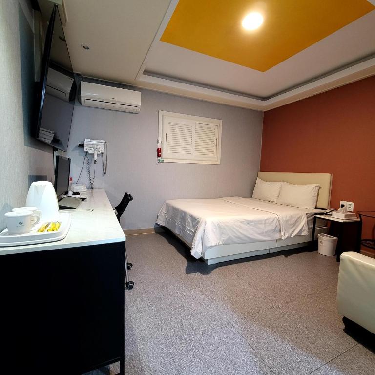 a room with a bed and a desk and a television at 스카이모텔 in Seoul