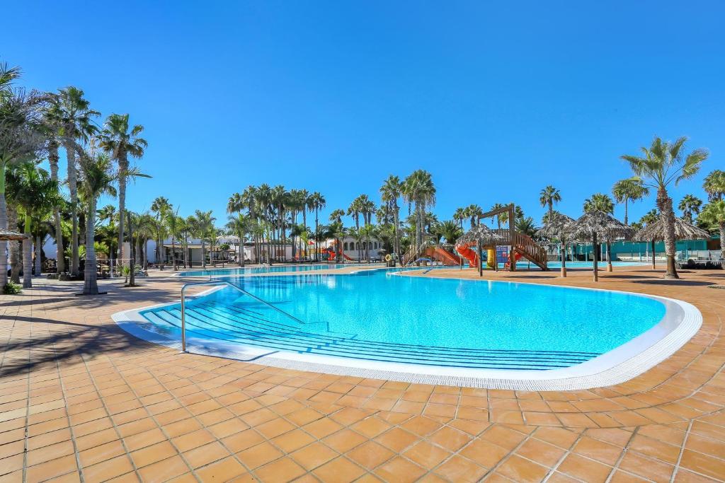una piscina in un resort con palme di Horizon blu a Corralejo