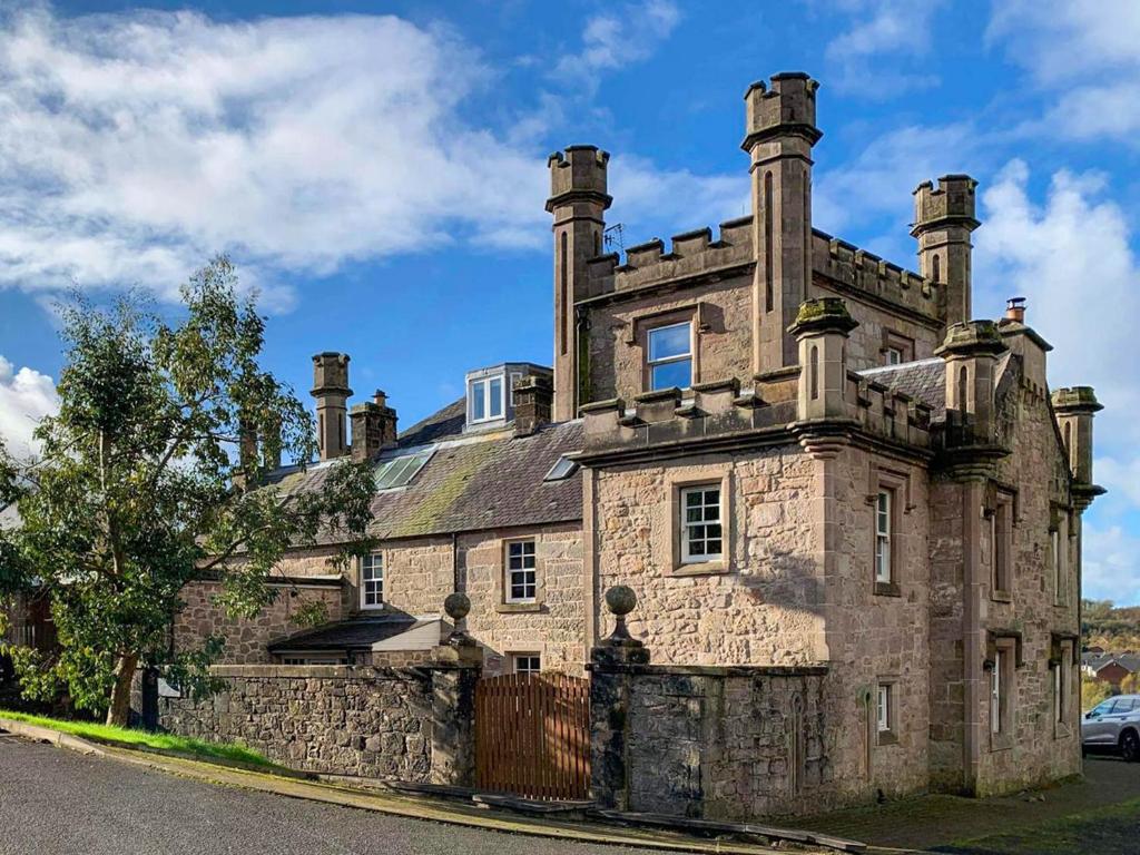 een oud stenen huis met twee schoorstenen bovenop bij 2 The Langhouse in Inverkip