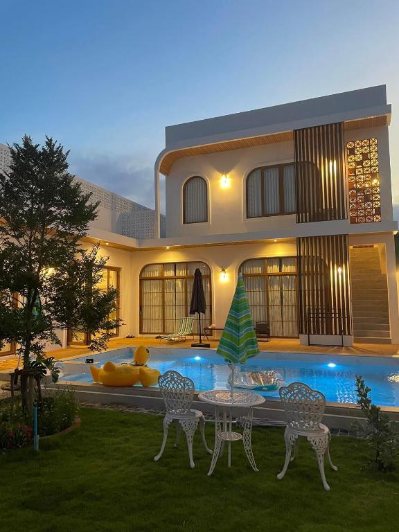 a house with a table and chairs in front of a pool at Villanarachaam in Cha Am