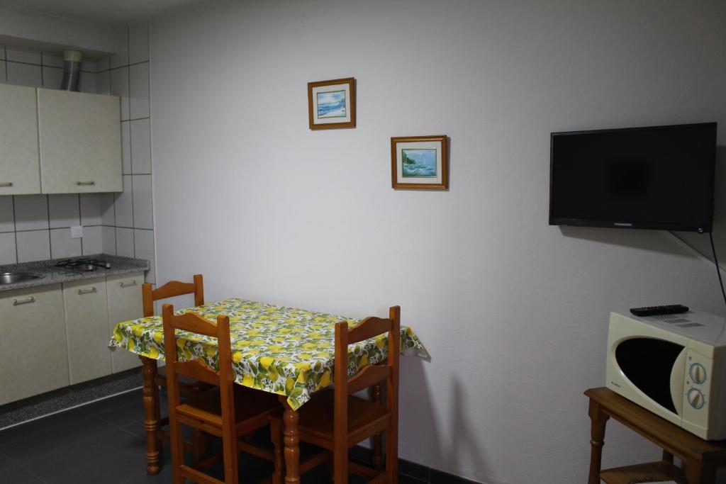 a kitchen with a table and two chairs and a tv at Apartamentos Bolonia Paraiso in Bolonia