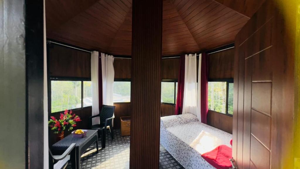 um quarto com uma cama e uma mesa e algumas janelas em LilliputHaven Treehut em Sultan Bathery